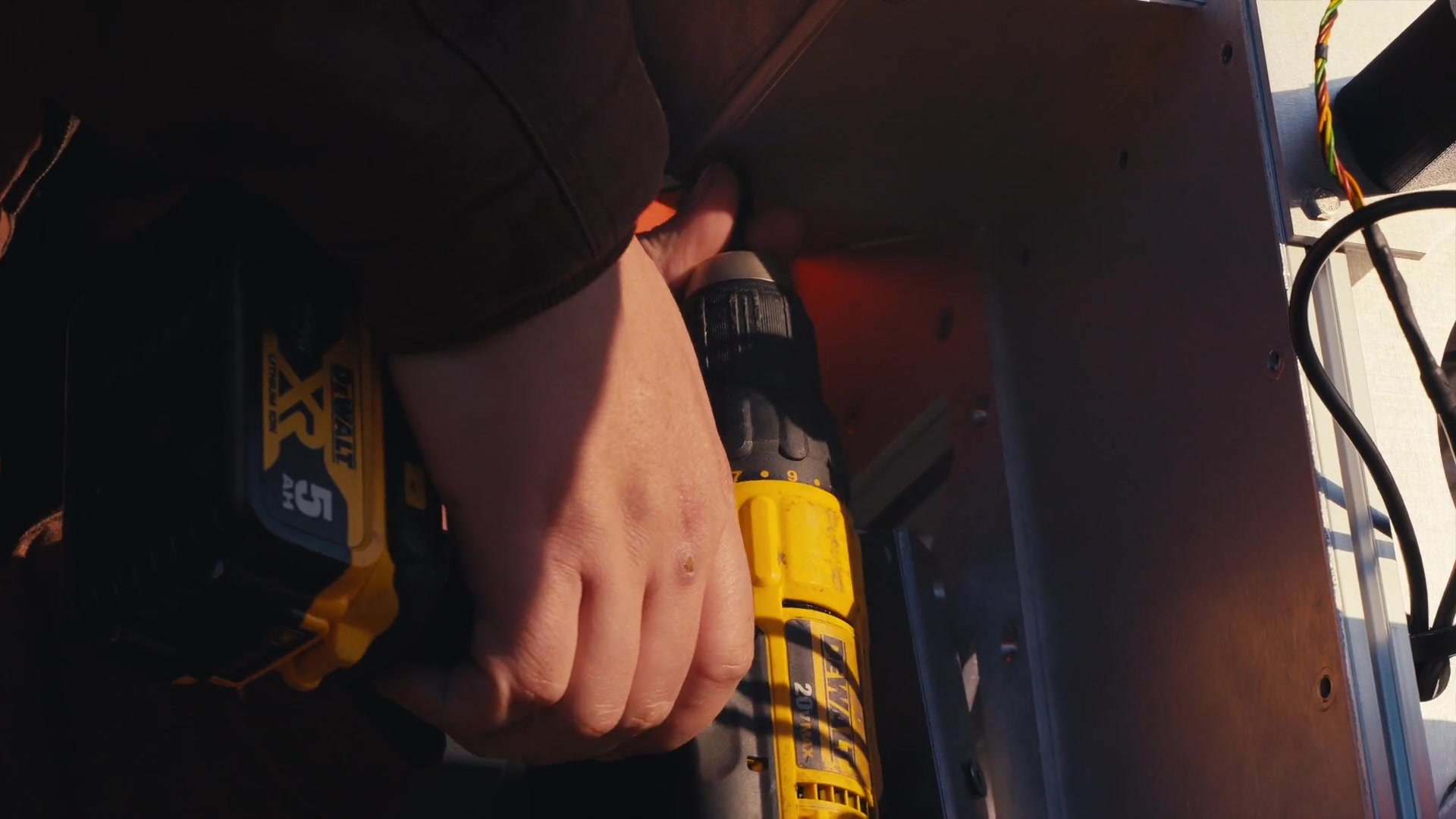 Documentary close-up of a hand installing fasteners on an enclosure